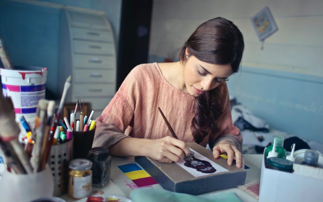 Kobieta siedząca przy biurku i malująca obraz